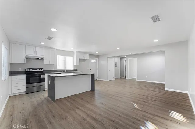 a large kitchen with a wooden floor and stainless steel appliances