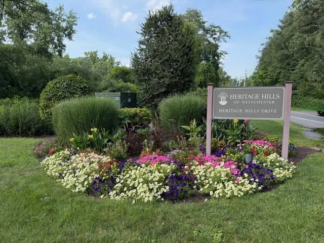 a view of a sign board with yard and green space