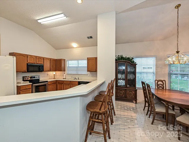 a kitchen with stainless steel appliances kitchen island granite countertop a table chairs stove a sink and dishwasher