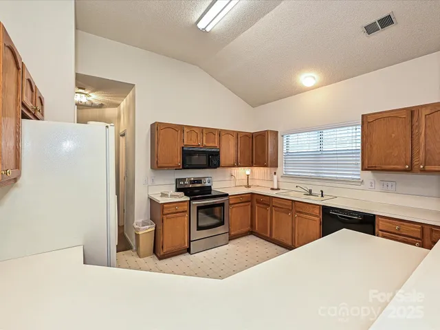 a kitchen with stainless steel appliances granite countertop a stove top oven a sink a refrigerator white cabinets and wooden floor