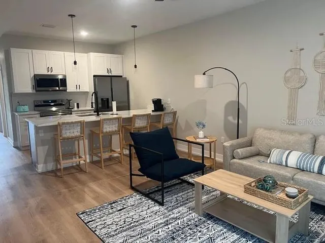 a living room with furniture a rug and kitchen view