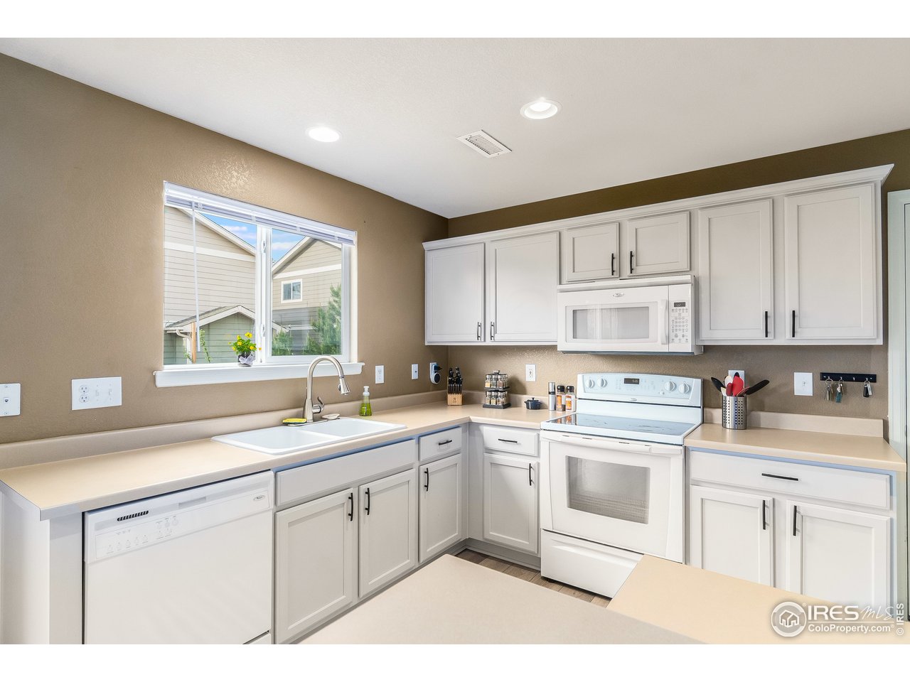 10435 Lower Ridge Road Longmont, CO 80504 - Photo 8 of 26 a kitchen with a sink white cabinets and white appliances