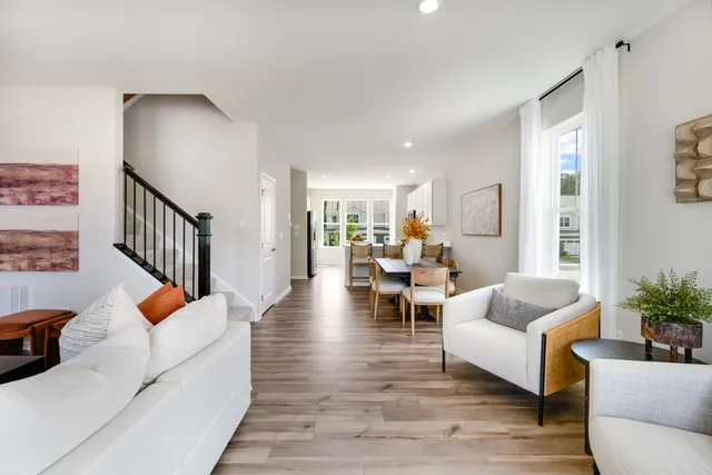 a living room with furniture and a dining table with wooden floor