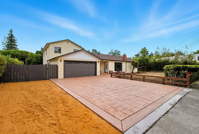 a backyard of a house with table and chairs with wooden fence