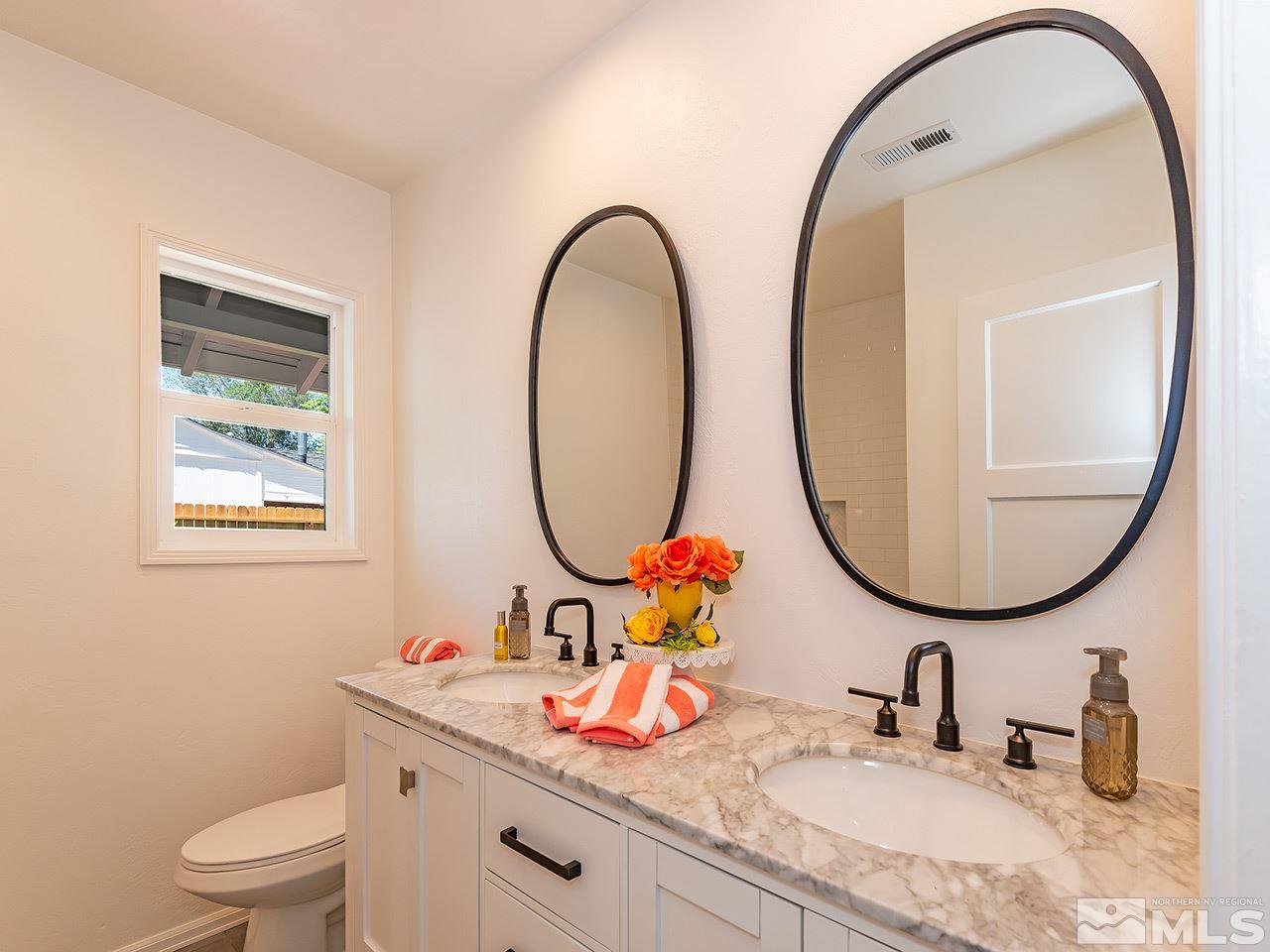 1055 Primrose Street Reno, NV 89509 - Photo 20 of 26 a bathroom with a granite countertop toilet a sink and a mirror