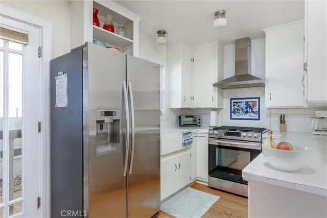 a kitchen with stainless steel appliances a refrigerator a sink and white cabinets