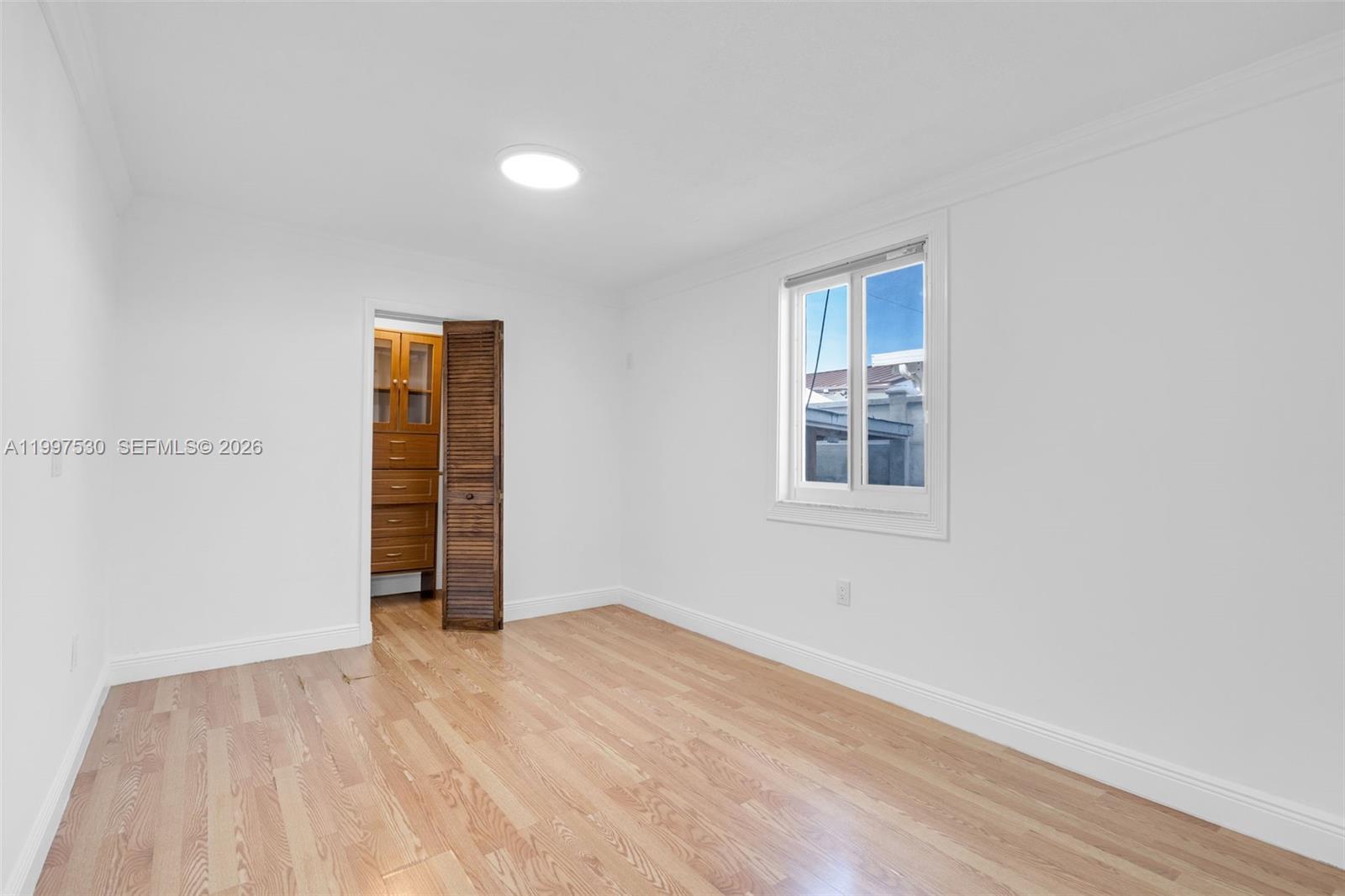 201 Southwest 51st Court, Unit 2 Miami, FL 33134 - Photo 7 of 10 a view of an empty room with wooden floor and a window