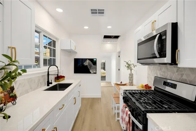 a kitchen with stainless steel appliances a stove a sink a microwave and cabinets