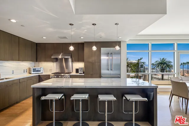 a kitchen with a stove a sink a refrigerator and chairs