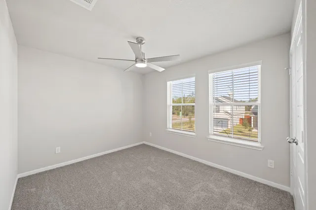 an empty room with windows and fan