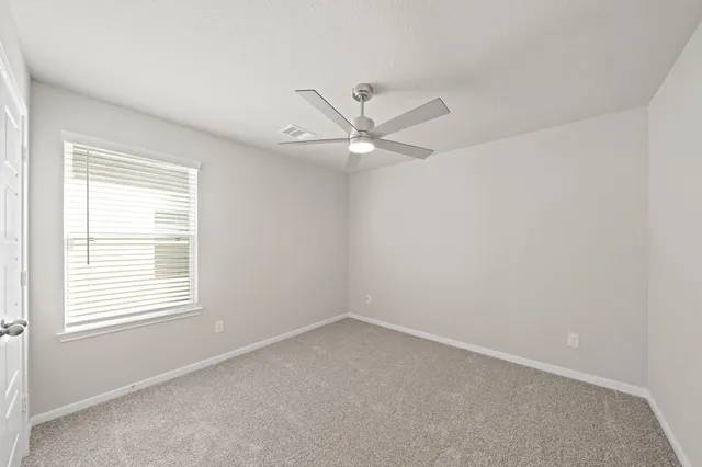 an empty room with a window and a ceiling fan