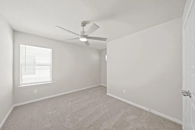 an empty room with a window and a fan