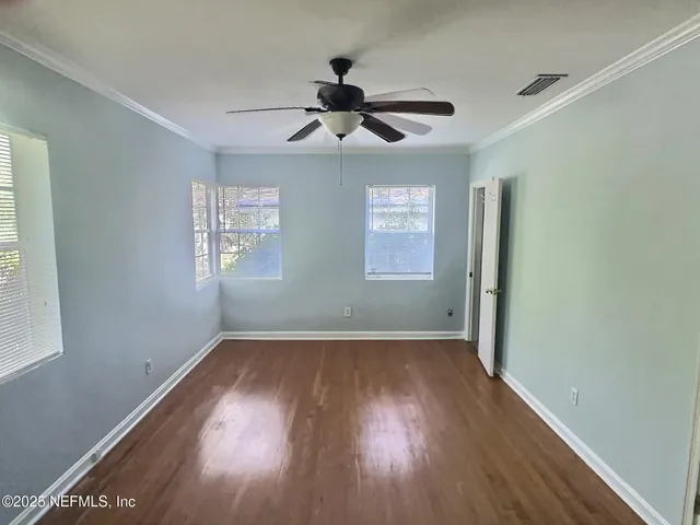 a view of empty room with wooden floor and fan