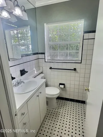 a bathroom with a sink a toilet a window and vanity