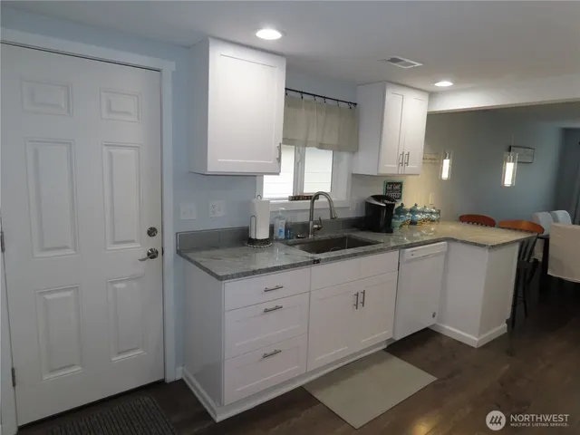 a kitchen with granite countertop white cabinets and sink