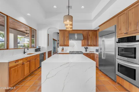 a large kitchen with stainless steel appliances kitchen island granite countertop a stove a sink dishwasher and a refrigerator with wooden floor