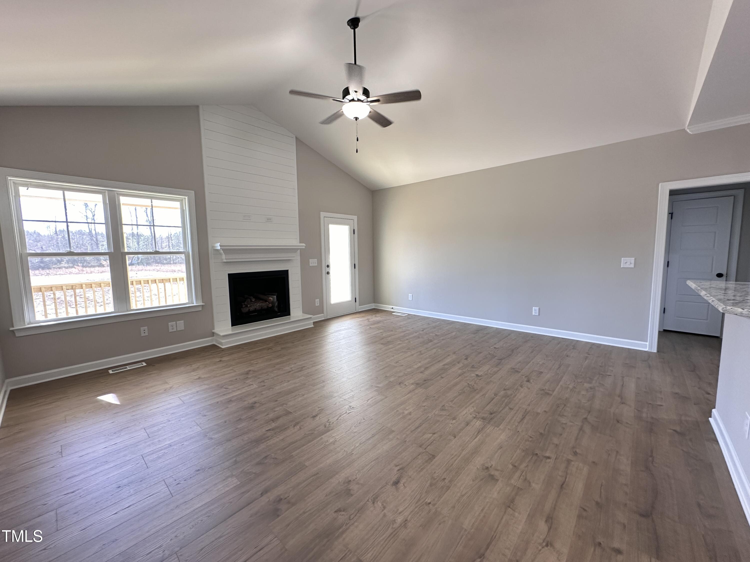 180 Pepperdam Street Smithfield, NC 27577 - Photo 2 of 8 an empty room with wooden floor fireplace and windows