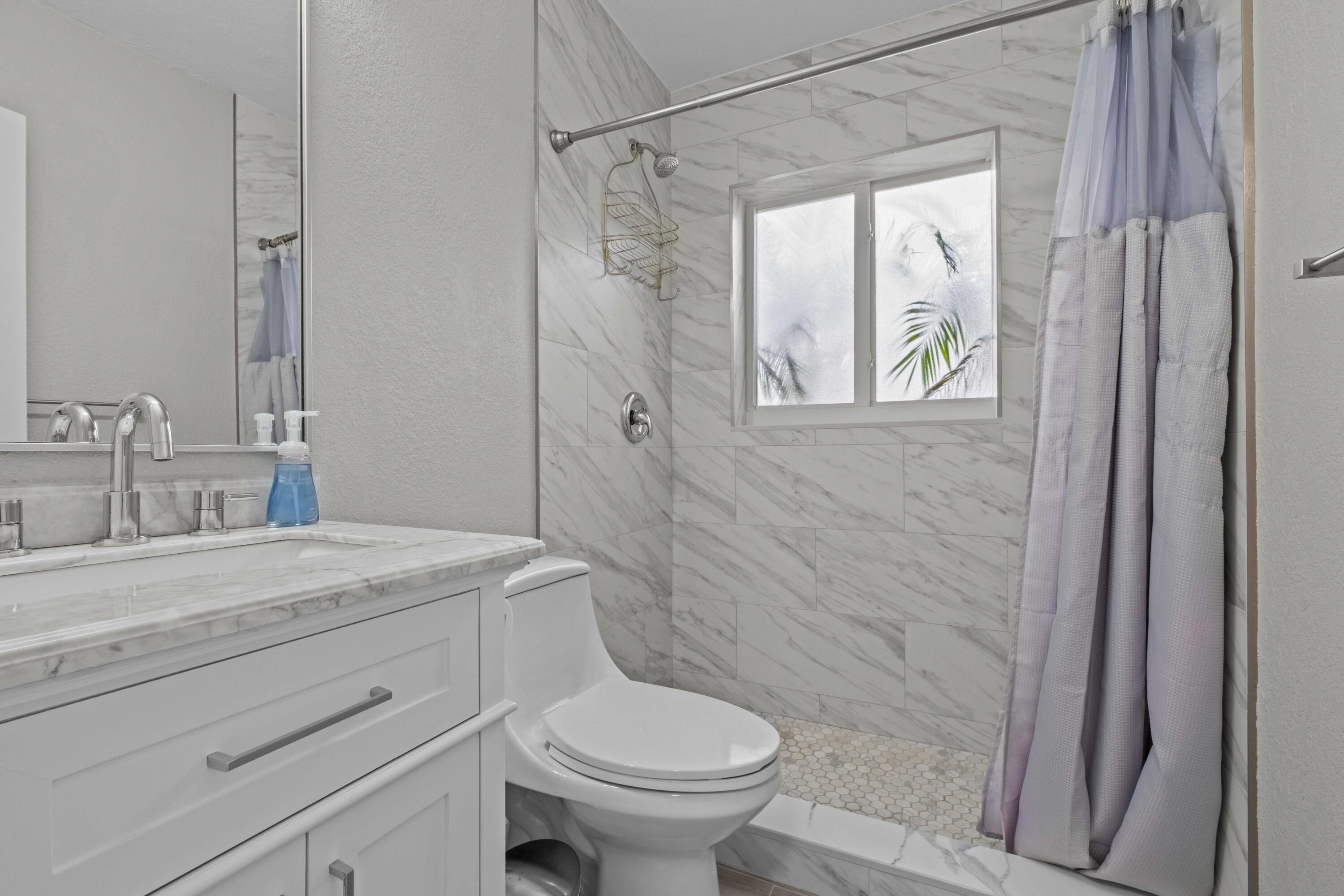1007 Northeast 9th Court Pompano Beach, FL 33060 - Photo 16 of 21 a bathroom with a granite countertop sink a toilet and a shower