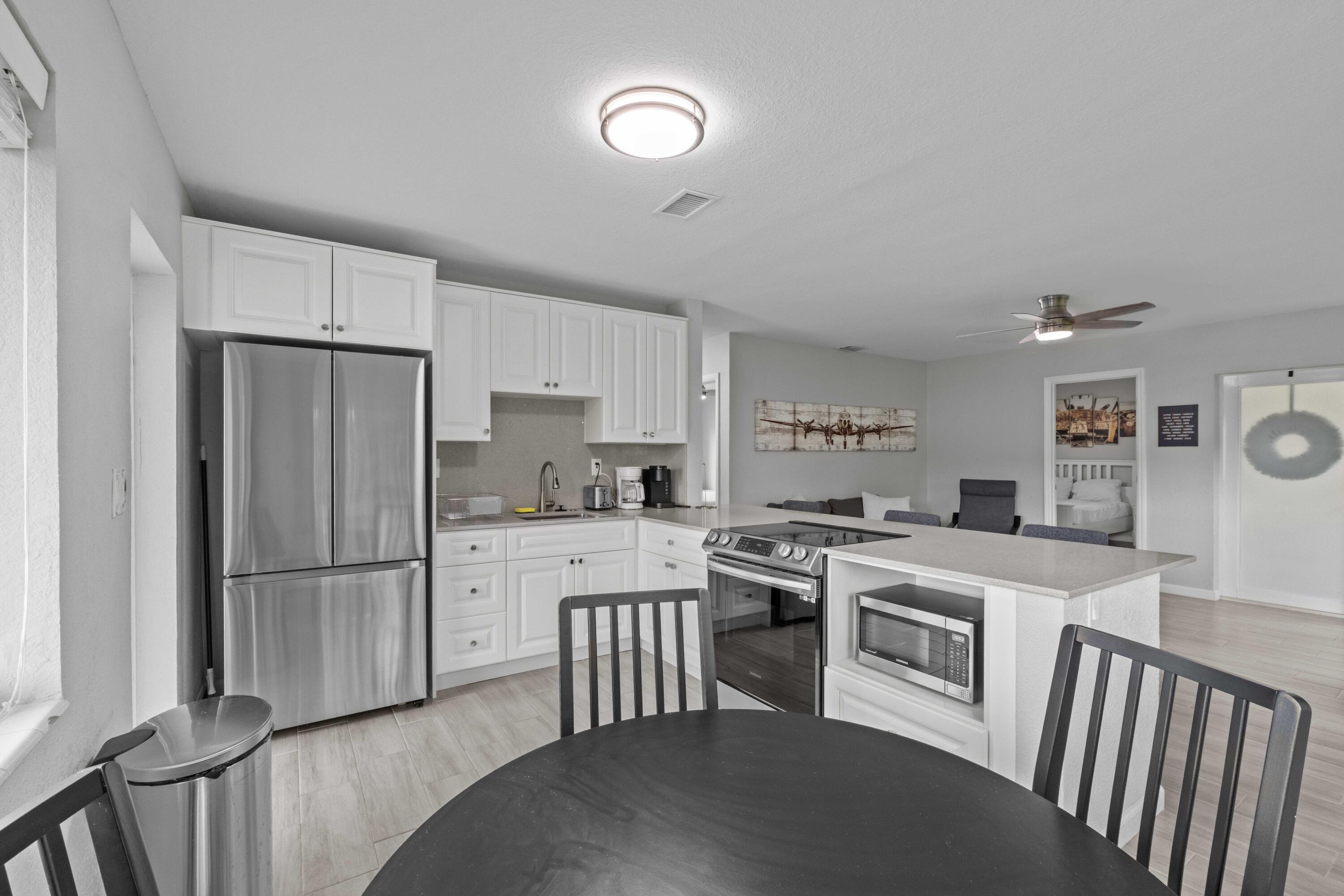 1007 Northeast 9th Court Pompano Beach, FL 33060 - Photo 7 of 21 a kitchen with a refrigerator a stove a sink dishwasher and white cabinets with wooden floor