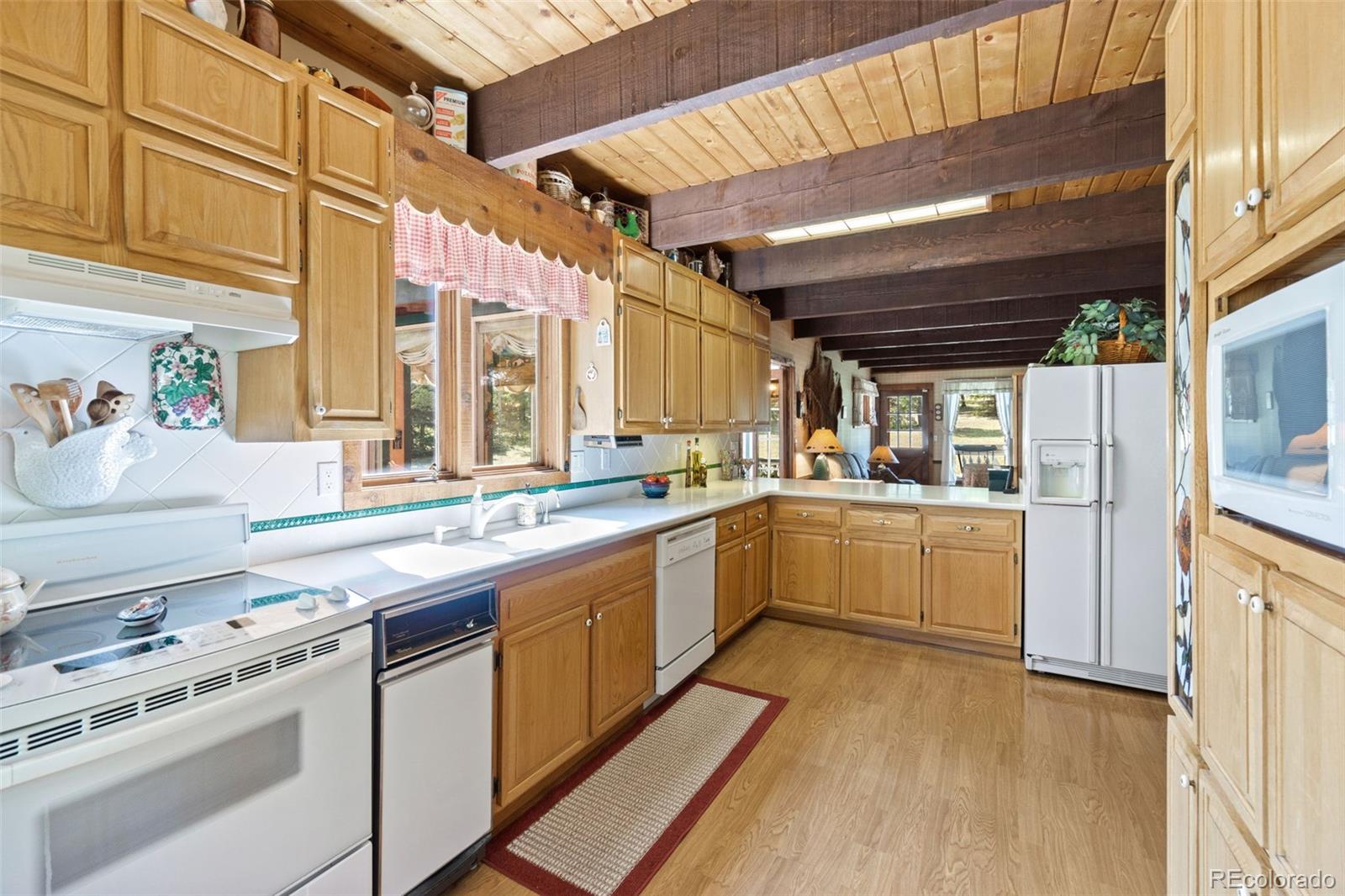 600 Old Squaw Pass Road Evergreen, CO 80439 - Photo 10 of 40 a kitchen that has a lot of white cabinets and wooden floor