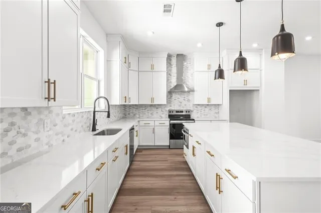 a kitchen with stainless steel appliances a stove a sink a refrigerator a center island and a window