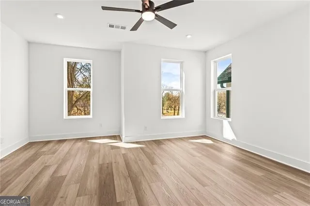 a view of empty room with wooden floor and fan