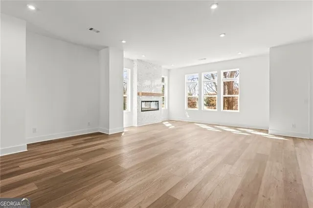 a view of an empty room with a window and wooden floor