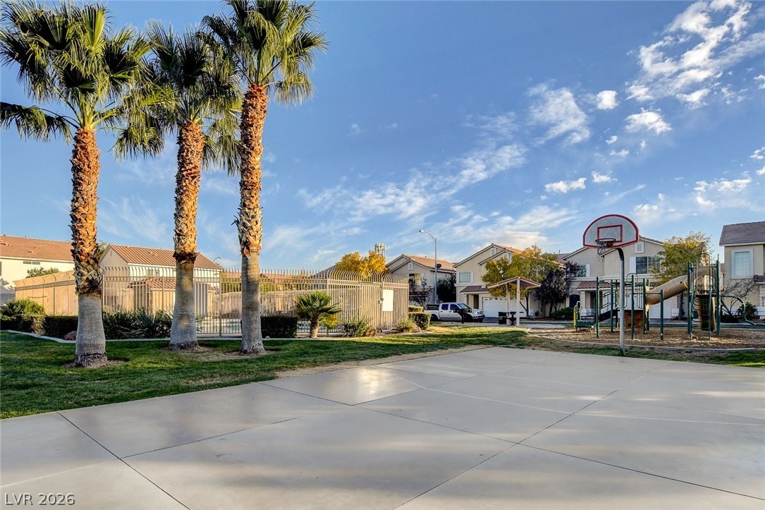 7259 Cestrum Road Las Vegas, NV 89113 - Photo 33 of 35 A community recreation area features a basketball court, playground, and tropical landscaping, with homes in the background.