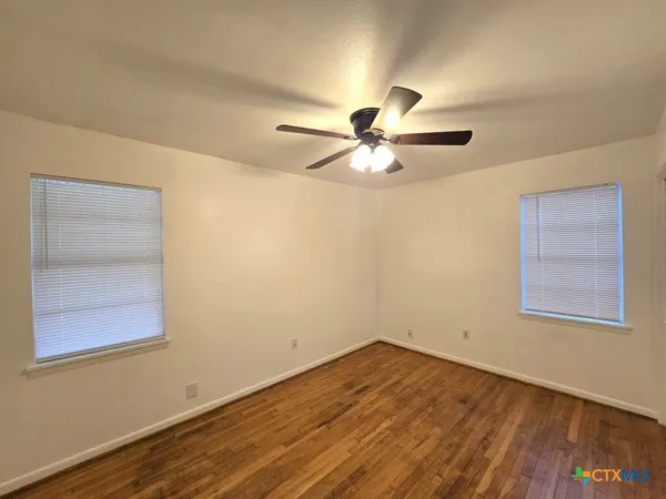 an empty room with a window and a ceiling fan