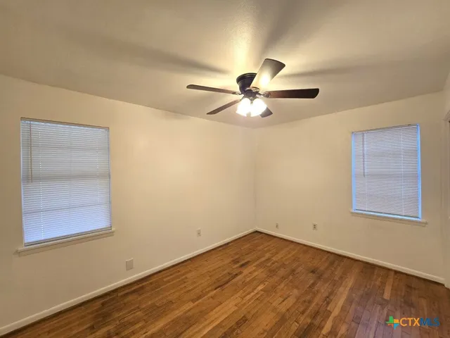 an empty room with a window and a ceiling fan
