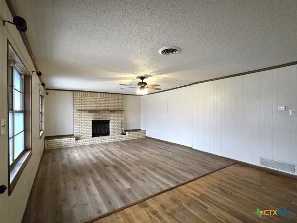 a view of empty room with wooden floor and fireplace