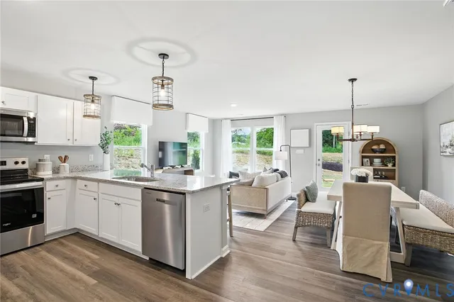 a kitchen with kitchen island granite countertop a stove a sink a dining table and chairs with wooden floor