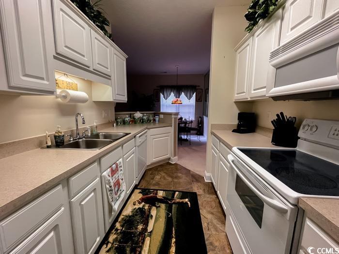 1101 Peace Pipe Place, Unit 104 Myrtle Beach, SC 29579 - Photo 19 of 22 Kitchen with white appliances, a sink, light countertops, and white cabinets