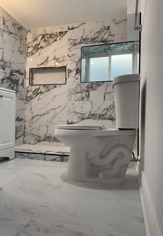 a white toilet sitting next to a shower