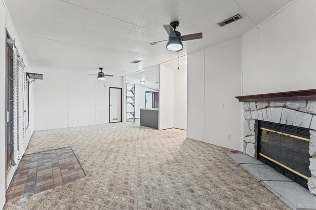 a view of empty room with a fireplace and ceiling fan