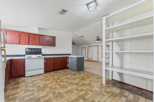 a kitchen with stainless steel appliances kitchen island granite countertop a refrigerator and a stove top oven