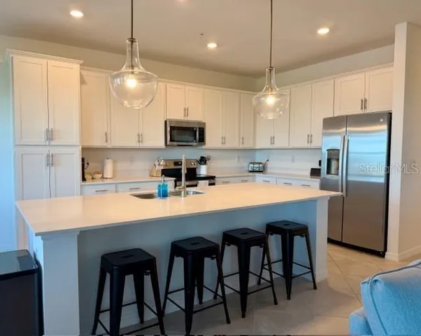 a kitchen with kitchen island granite countertop a sink a center island and stainless steel appliances