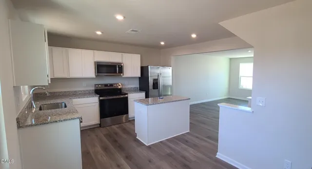 a kitchen with granite countertop a refrigerator stove top oven and sink