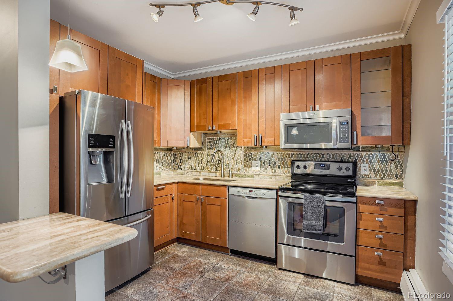 960 Sherman Street, Unit 1B Denver, CO 80203 - Photo 5 of 25 a kitchen with stainless steel appliances granite countertop a refrigerator stove microwave and sink
