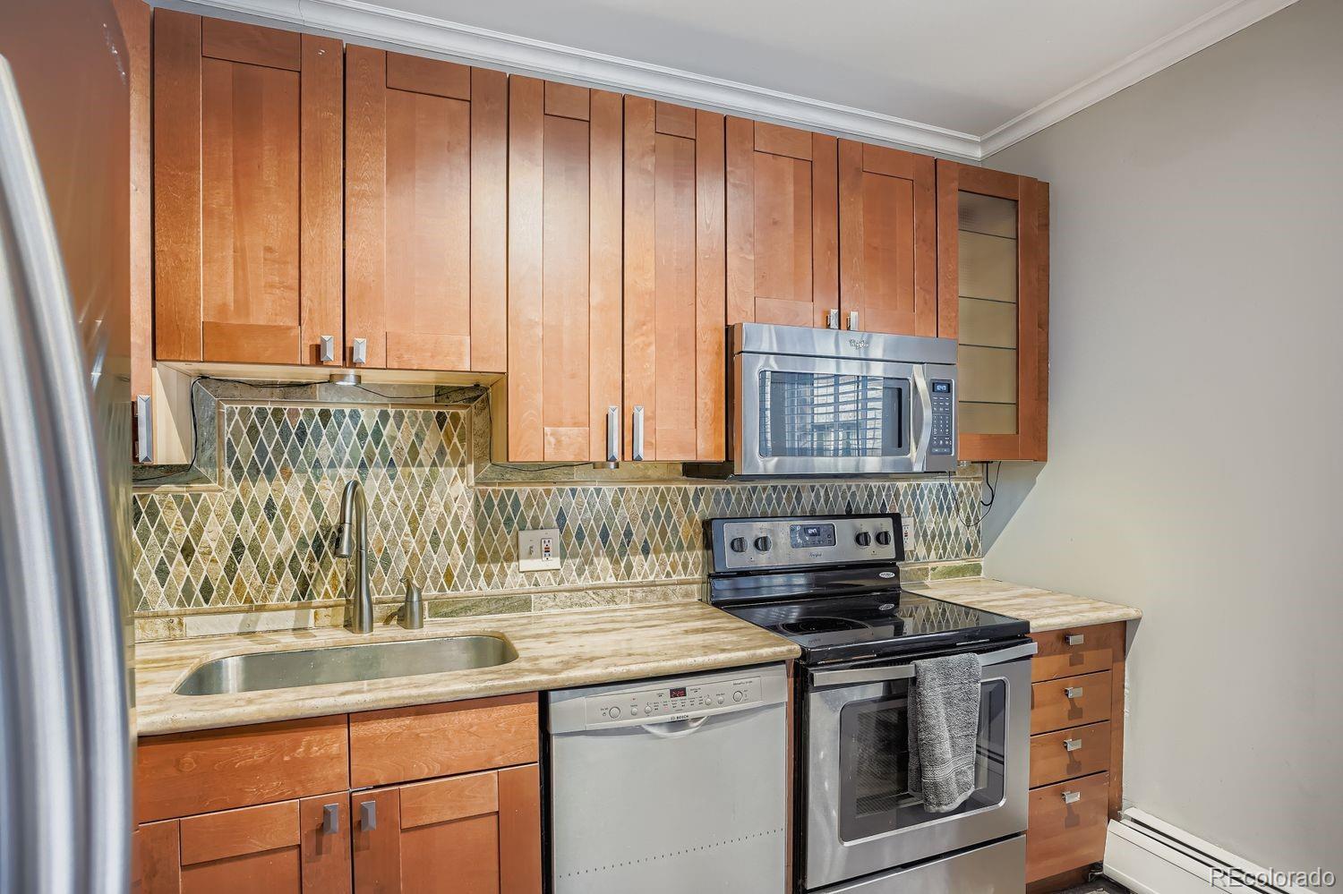 960 Sherman Street, Unit 1B Denver, CO 80203 - Photo 7 of 25 a kitchen with a stove and a white cabinets