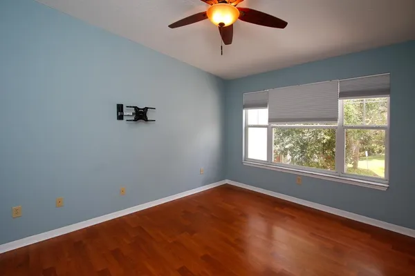 an empty room with a window and a ceiling fan