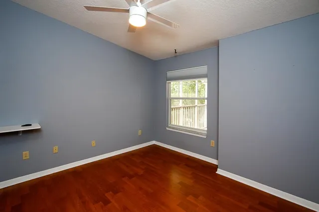 an empty room with wooden floor and windows