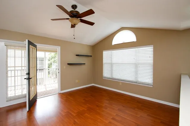 a view of an empty room with wooden floor and a window