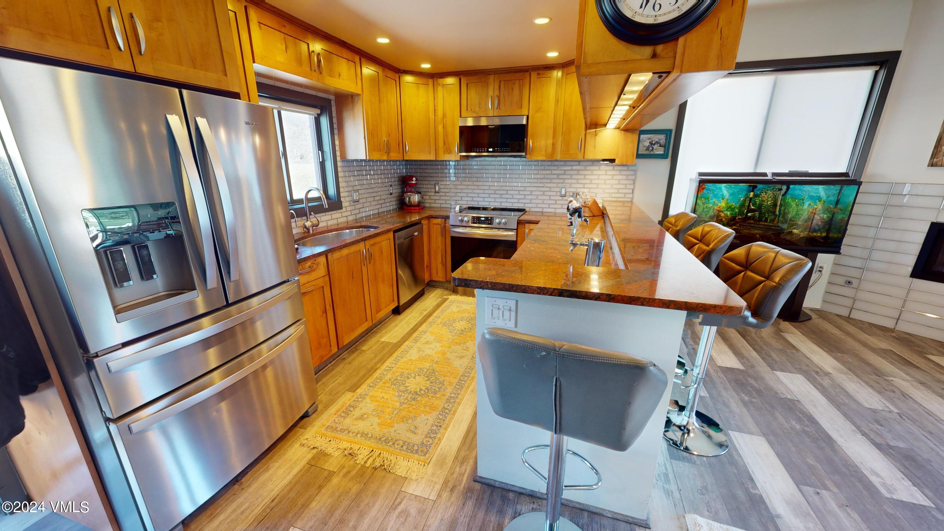 314 Eagle Road, Unit B1 Avon, CO 81620 - Photo 3 of 24 a kitchen with stainless steel appliances granite countertop a refrigerator a stove top oven a chimney and a dining table view