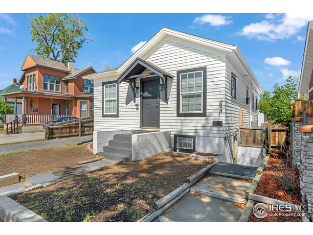 a view of a white house with a yard and potted plants