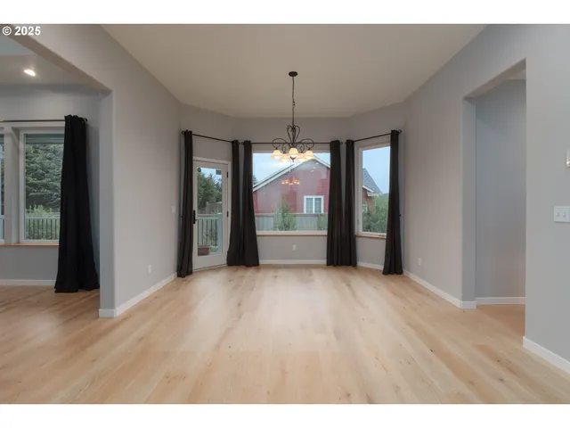 a view of an empty room with wooden floor and windows