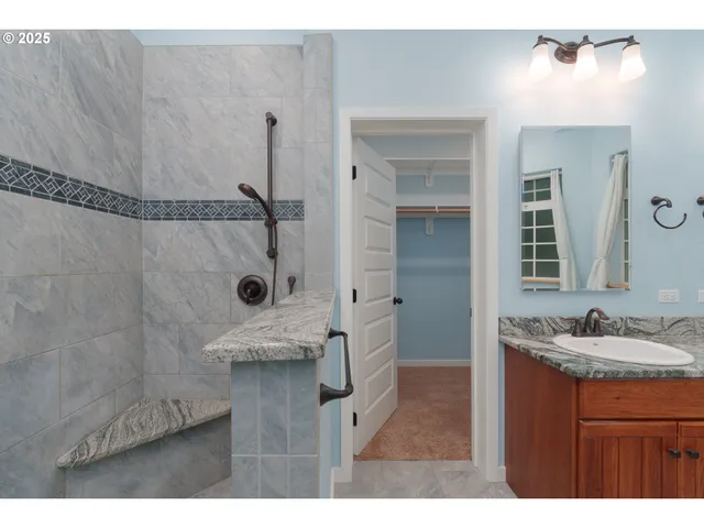 a bathroom with a granite countertop sink a mirror and shower