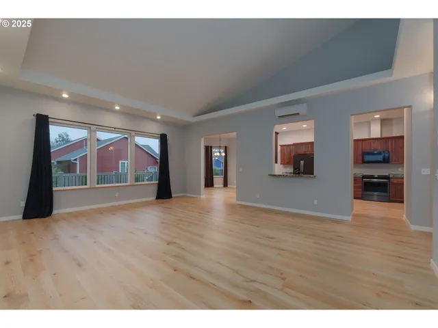 a view of an empty room with wooden floor and windows