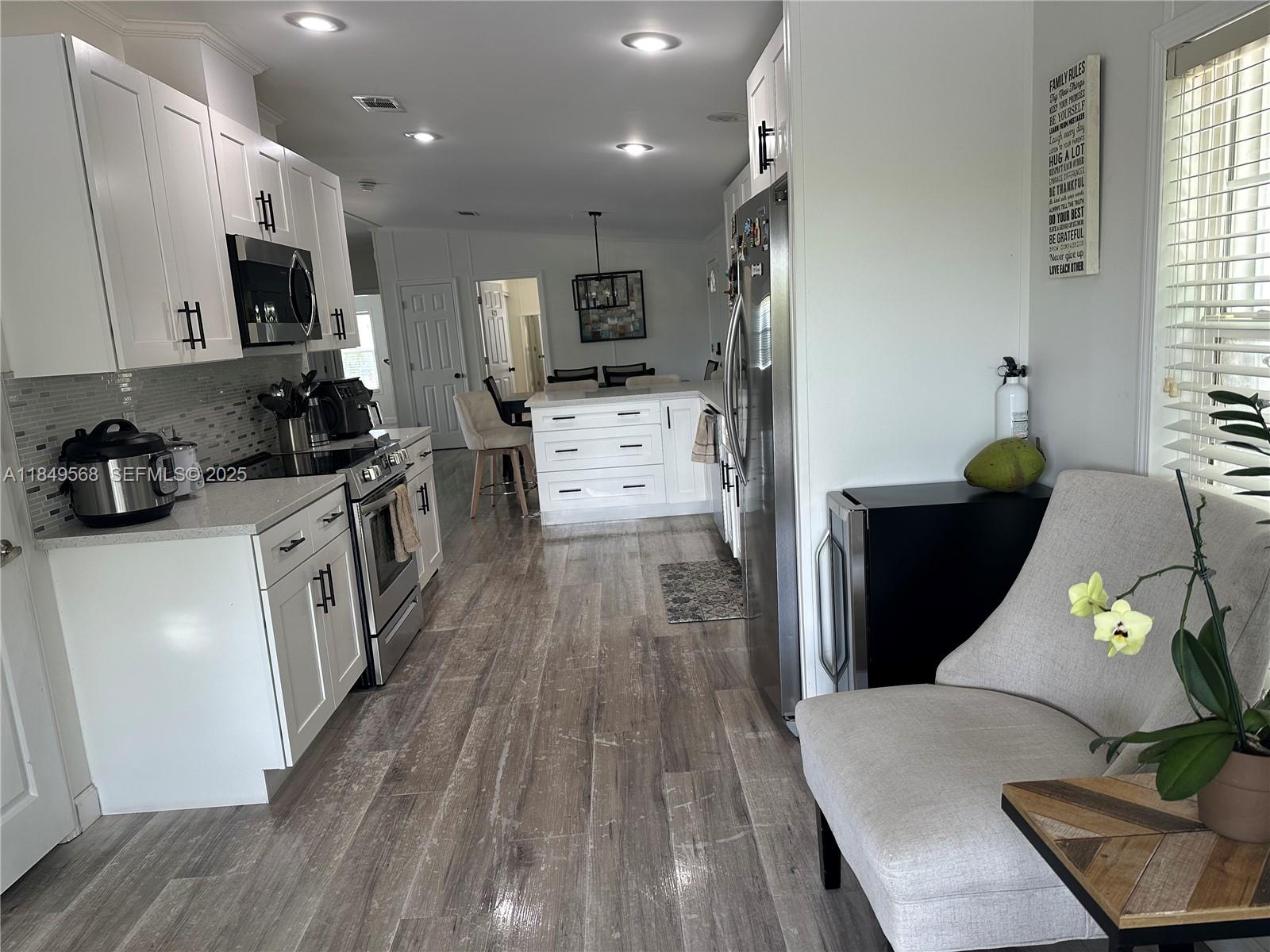 1570 Southwest 64th Way Boca Raton, FL 33428 - Photo 10 of 24 a kitchen with stainless steel appliances a stove a sink a microwave a refrigerator a cabinets and wooden floor