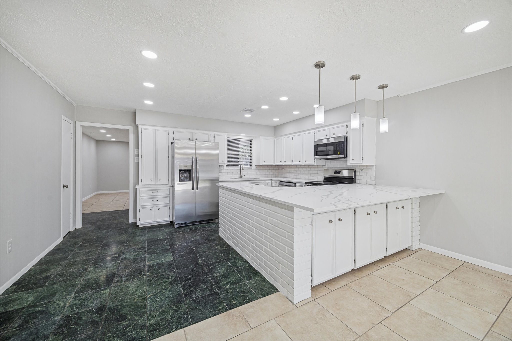 1703 Raintree Drive Baytown, TX 77520 - Photo 5 of 17 a large white kitchen with a refrigerator a stove top oven and white cabinets